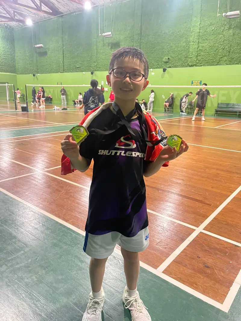 One of Ken's students holding a medal on court