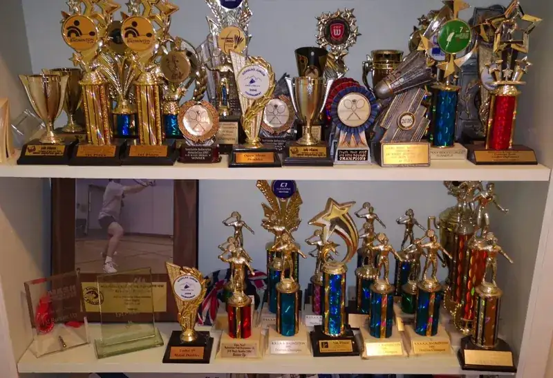 A shelf of badminton trophies and medals